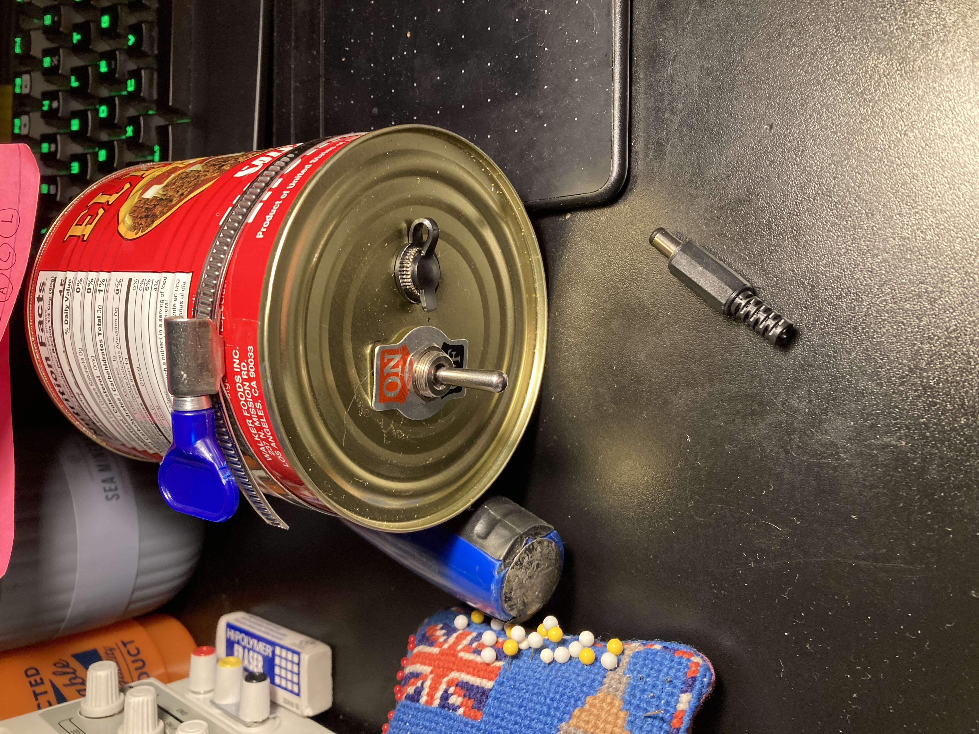 the flat bottom of the can, with a toggle switch and barrel port protruding through it