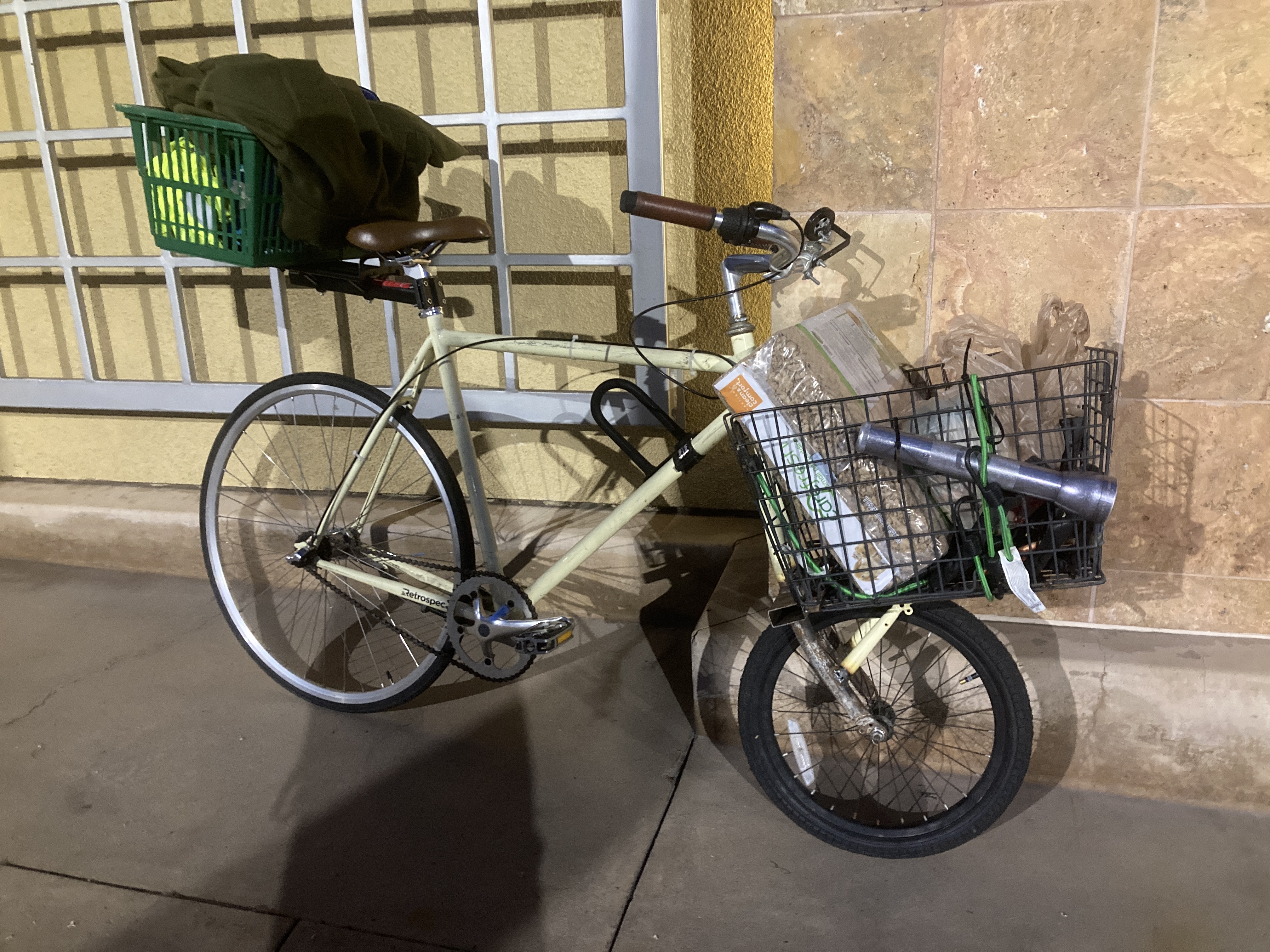 bike with a large rear wheel and small front wheel. a welded platform supports a large wire basket above the front wheel. a maglite flashlight is bungee corded to the basket