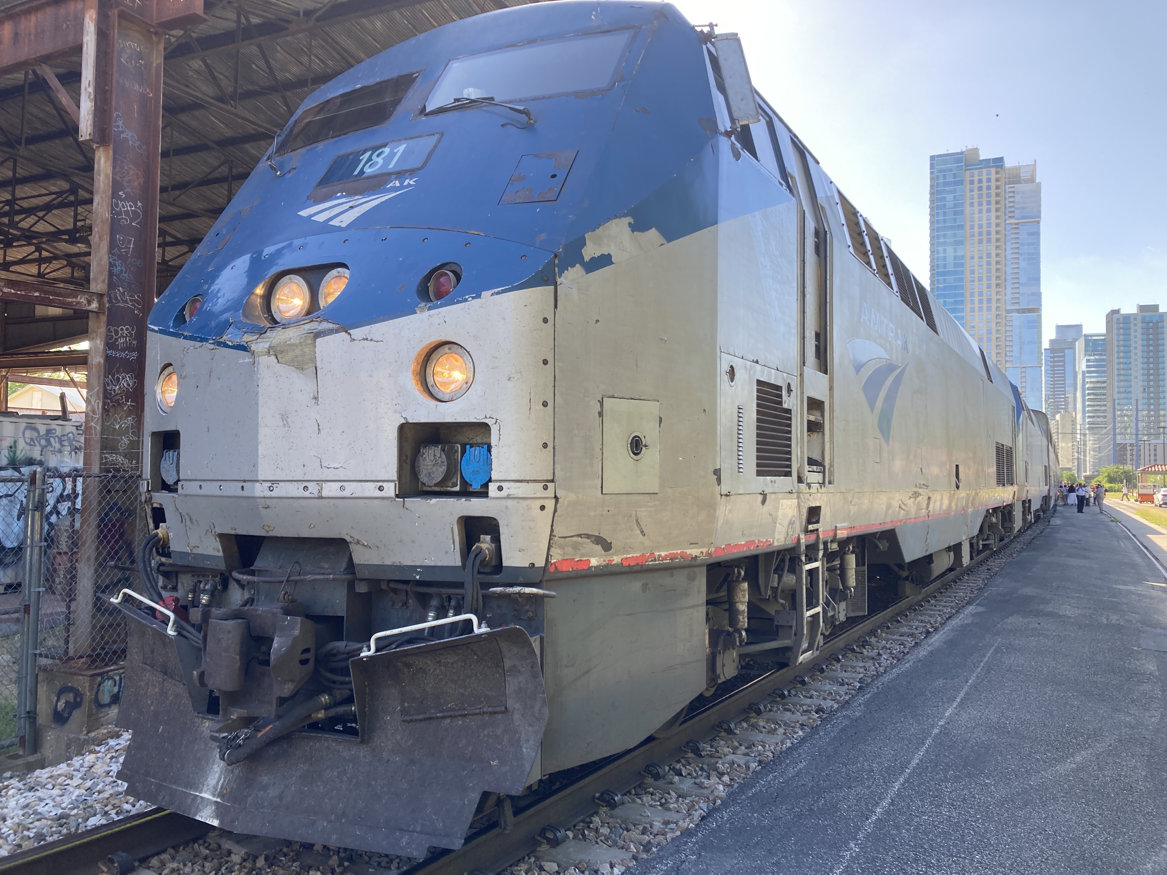 a train led by two GE genesis locmotives, with high rises in the distance