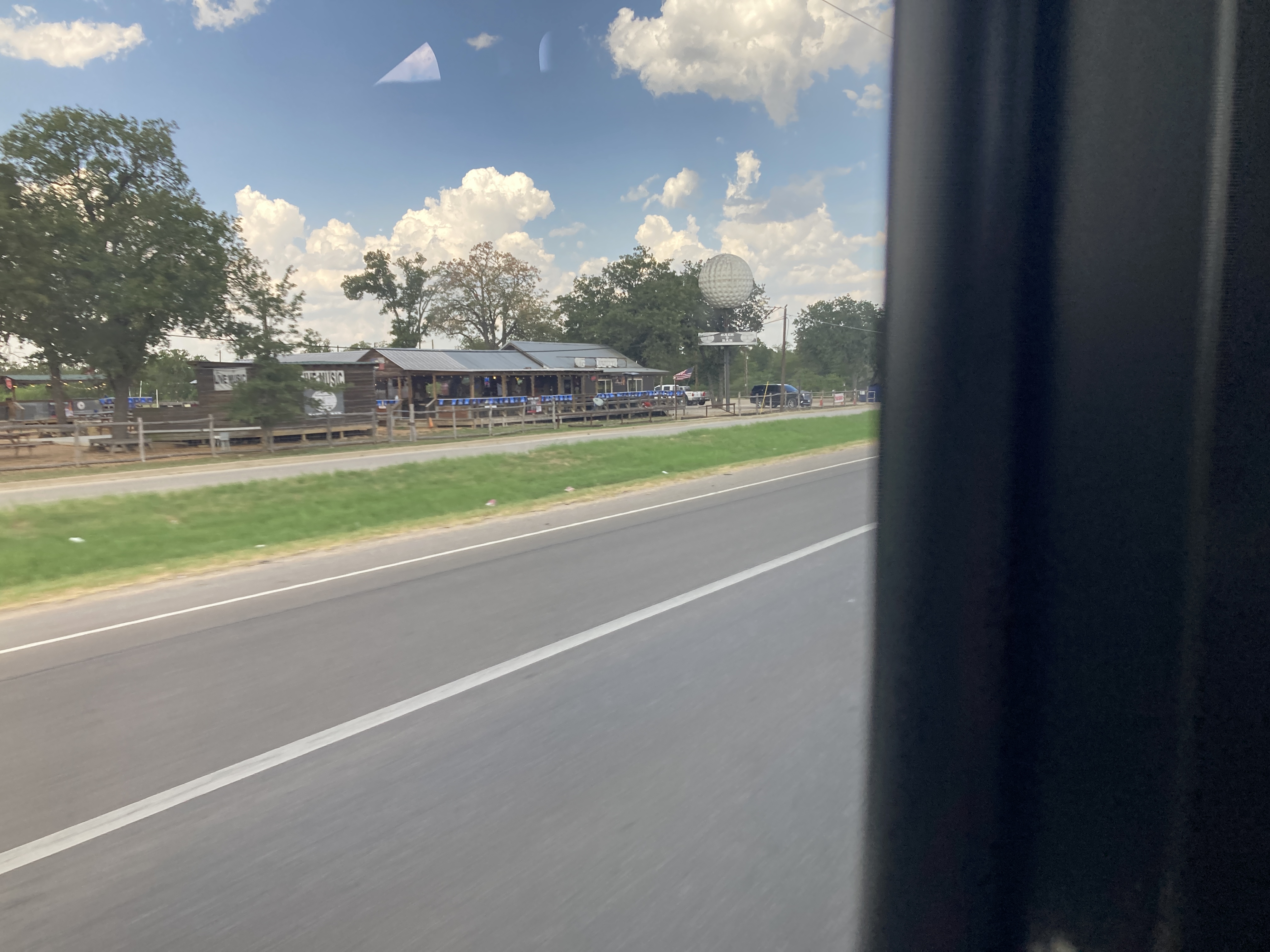 out the bus window, some sort of shop with a giant golf ball sculpture on a podium 