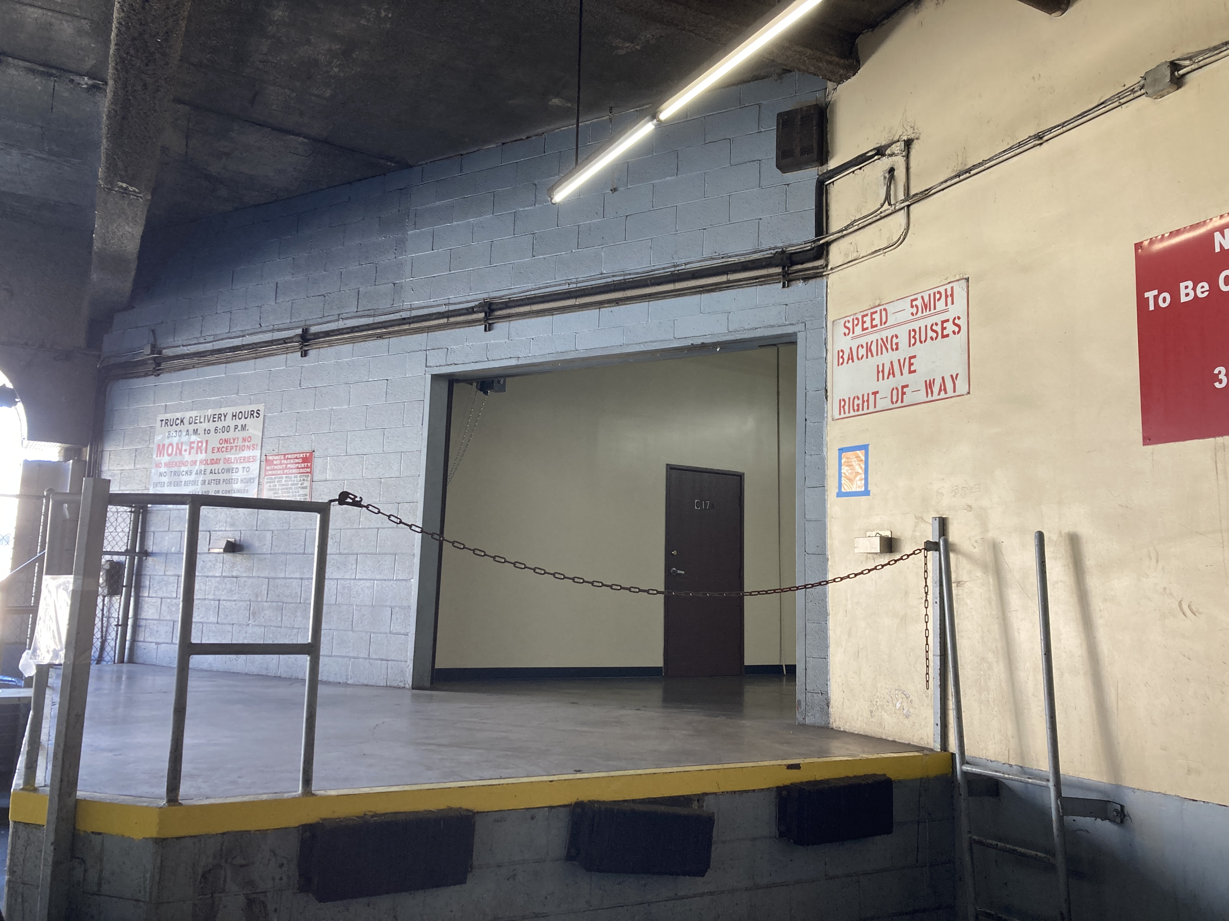 a loading dock in a corner of the upper level. it has a stencilled red and white sign reading SPEED - 5 MPH - BACKING BUSES HAVE RIGHT OF WAY.