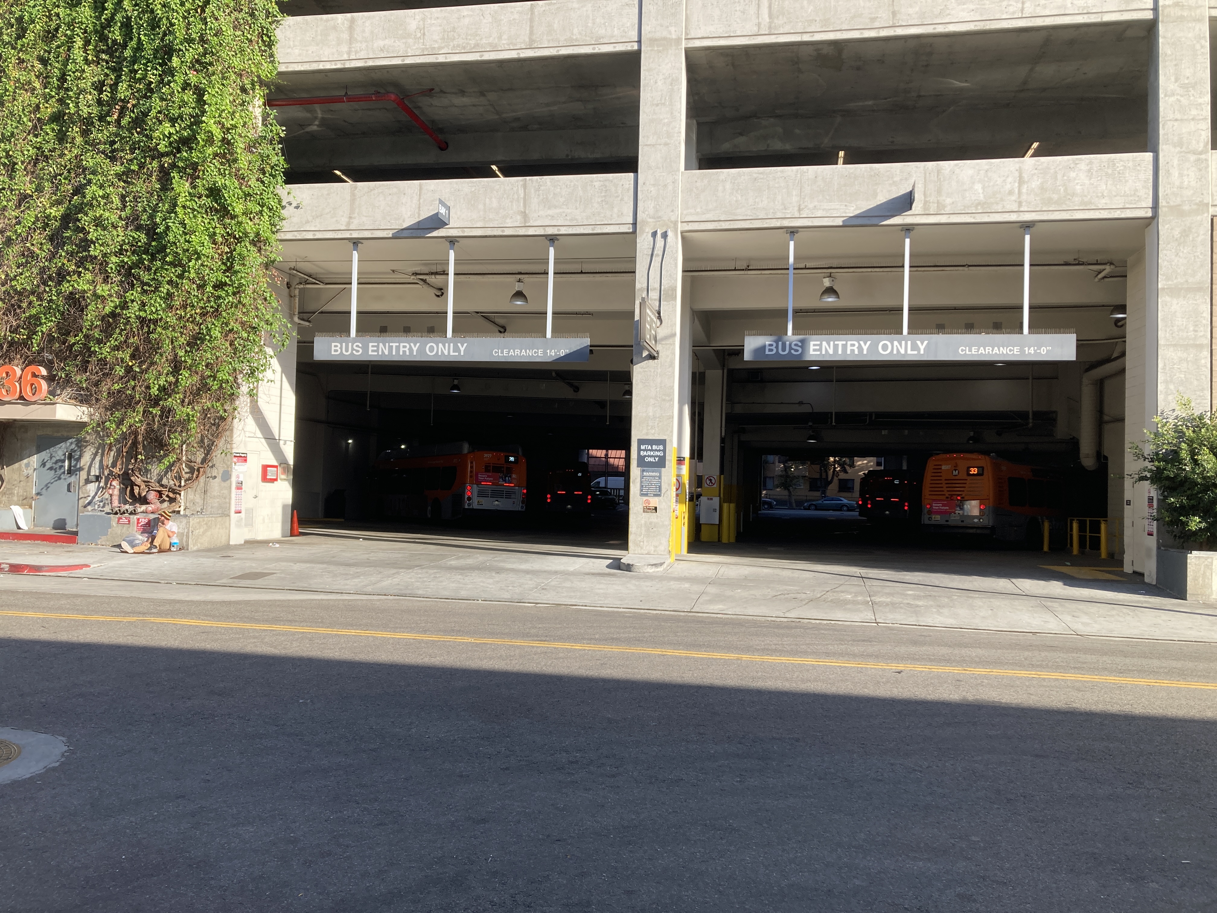 The ground floor entrance of a parking structure, signed BUS ENTRY ONLY, and five or six Metro buses can be seen waiting inside, numbered for routes 33 and 20